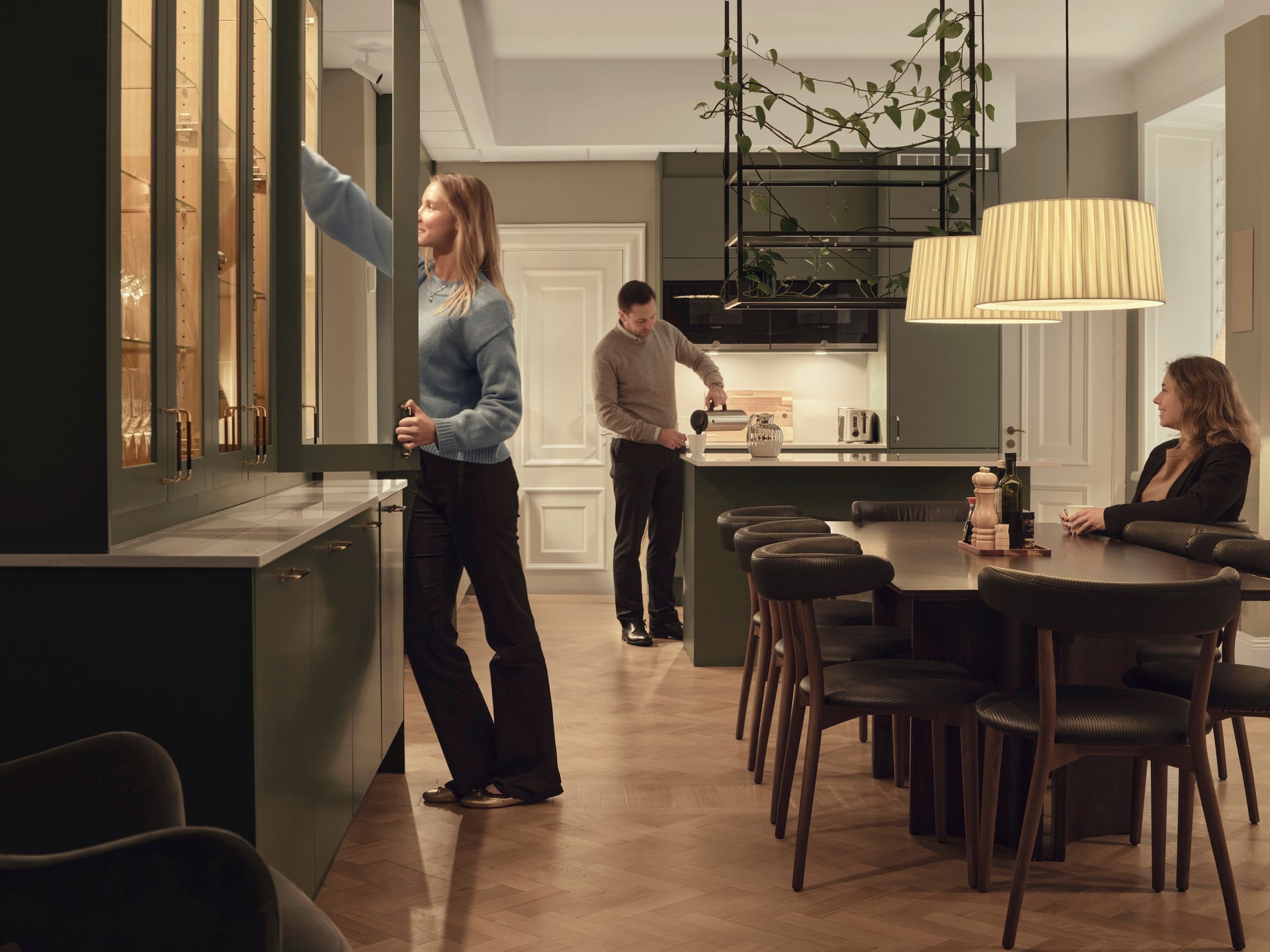 Pentry och matplats med långbord, köksö och barstolar i en modern kontorsmiljö.